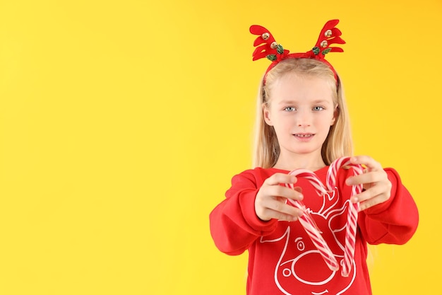 Petite fille avec des cannes de bonbon sur fond jaune