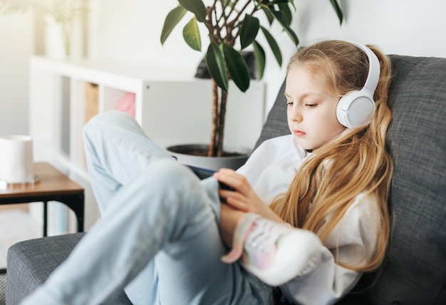 Petite fille avec un casque et une tablette à la maison