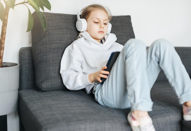 Petite fille avec un casque et une tablette à la maison