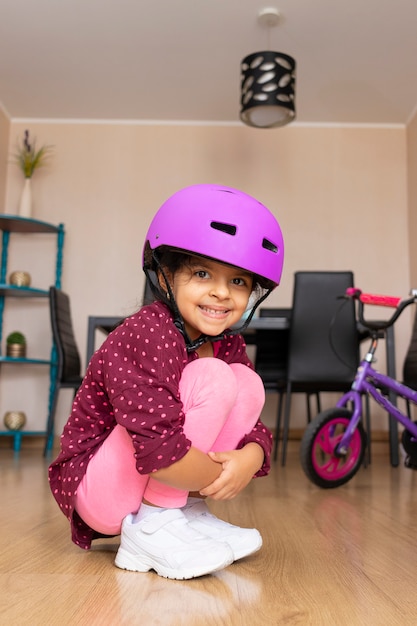 Petite fille avec un casque de vélo heureuse car elle fera du vélo à la maison