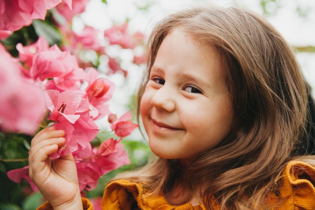 Petite fille caucasienne admirant le bougainvillier rose dans le jardin