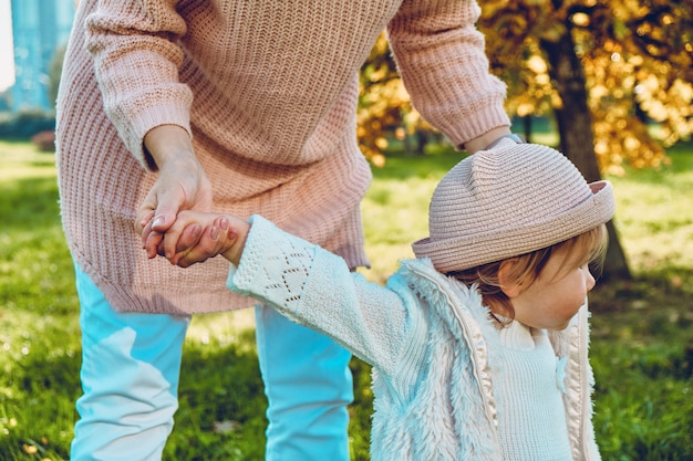 Petite fille caucasienne apprenant à marcher avec maman dans le parc.