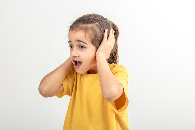 Petite fille caucasienne couvrait ses oreilles sur un fond blanc isolé