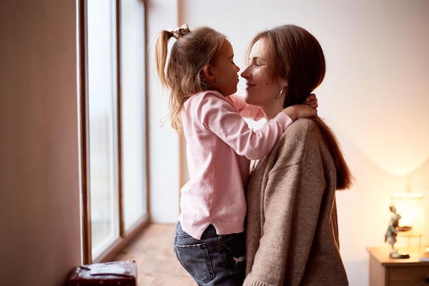 Petite fille caucasienne embrasse sa mère Concept de Noël famille heureuse