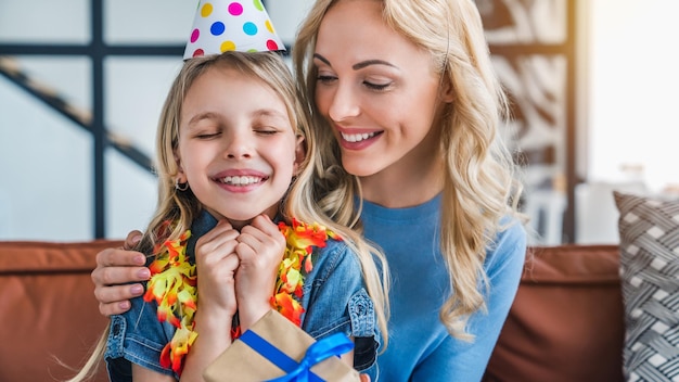 Une petite fille caucasienne excitée reçoit une boîte-cadeau de sa mère à la maison