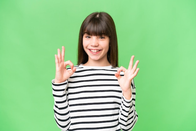 Petite fille caucasienne sur fond isolé montrant un signe ok à deux mains