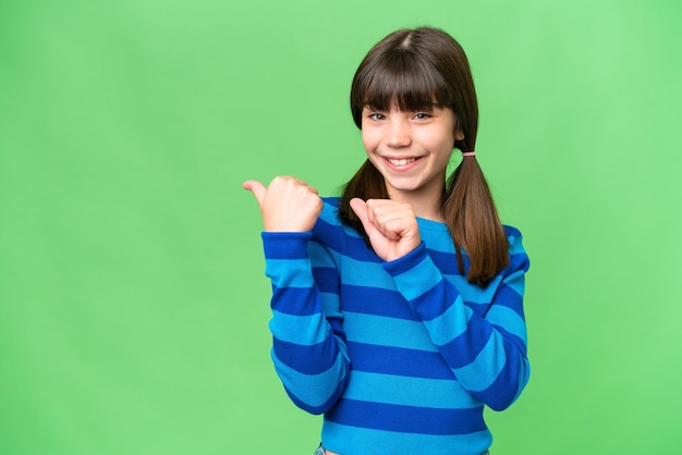 Petite fille caucasienne sur fond isolé pointant vers le côté pour présenter un produit