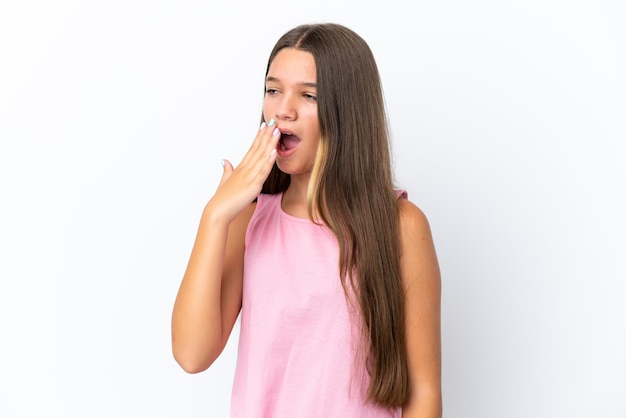 Petite fille caucasienne isolée sur fond blanc bâillant et couvrant la bouche grande ouverte avec la main