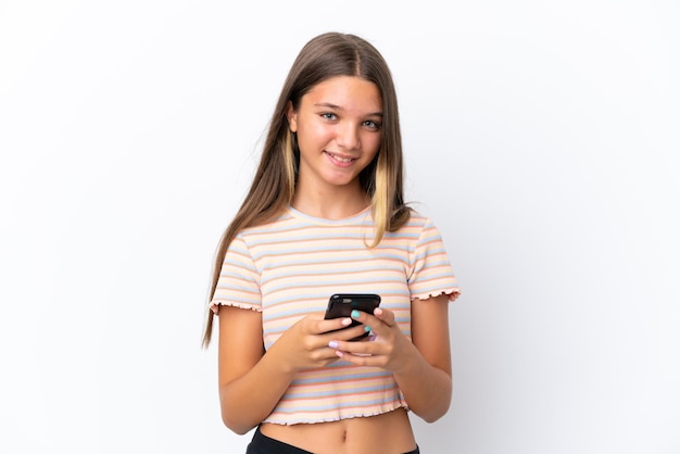 Petite fille caucasienne isolée sur fond blanc envoyant un message avec le mobile