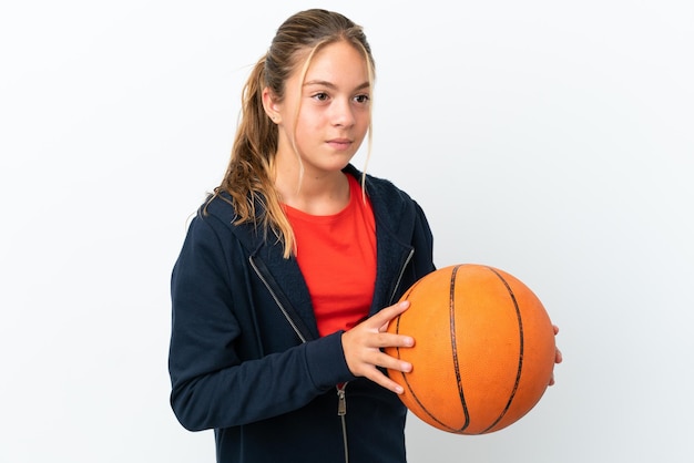 Petite fille caucasienne isolée sur fond blanc jouant au basket