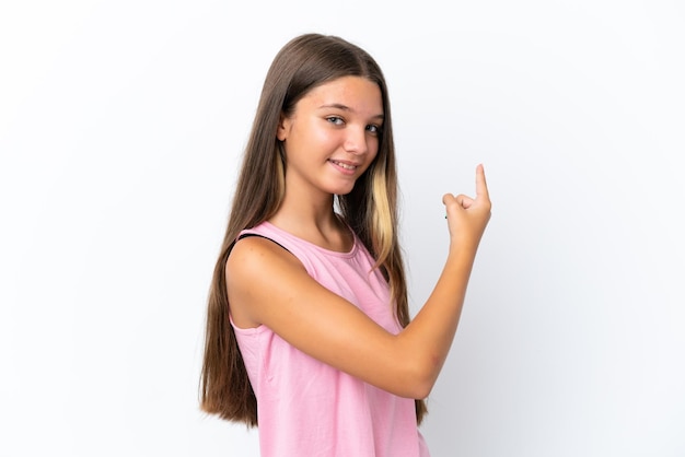 Petite fille caucasienne isolée sur fond blanc pointant vers l'arrière