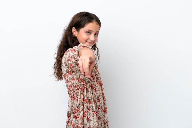 Petite fille caucasienne isolée sur fond blanc pointant vers l'avant avec une expression heureuse