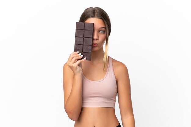 Petite fille caucasienne isolée sur fond blanc prenant une tablette de chocolat et surprise