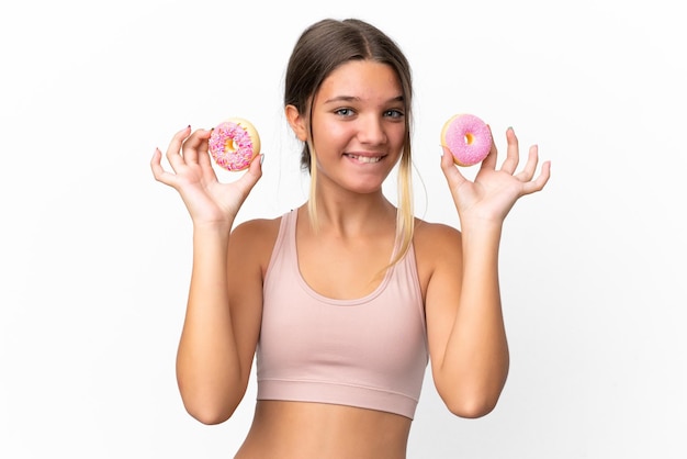 Petite fille caucasienne isolée sur fond blanc tenant des beignets