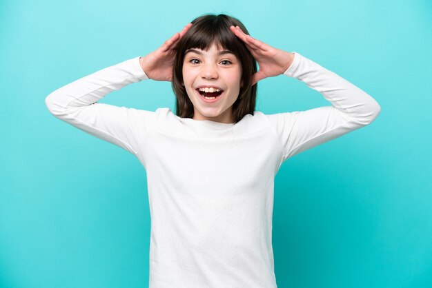 Petite fille caucasienne isolée sur fond bleu avec une expression surprise