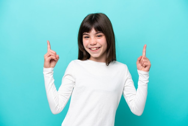 Petite fille caucasienne isolée sur fond bleu pointant vers une excellente idée