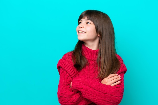 Petite fille caucasienne isolée sur fond bleu à la recherche sur le côté