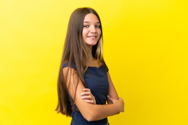 Petite fille caucasienne isolée sur fond jaune avec les bras croisés et impatient