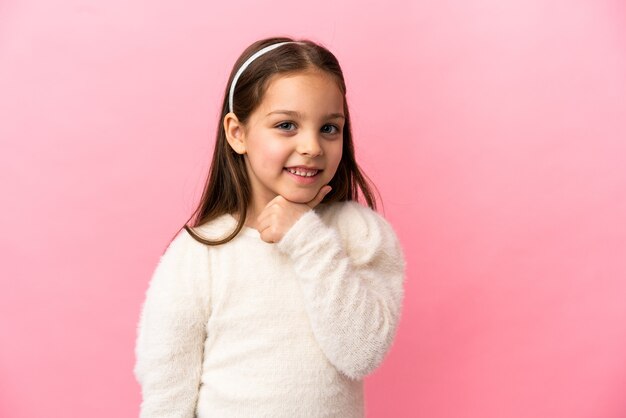 Petite fille caucasienne isolée sur fond rose à côté