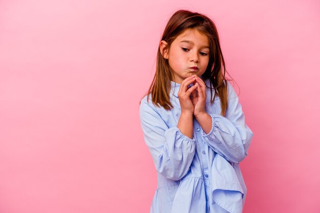 Petite fille caucasienne isolée sur fond rose, élaboration d'un plan en tête, mise en place d'une idée.