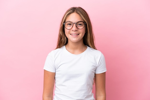 Petite fille caucasienne isolée sur fond rose avec des lunettes avec une expression heureuse