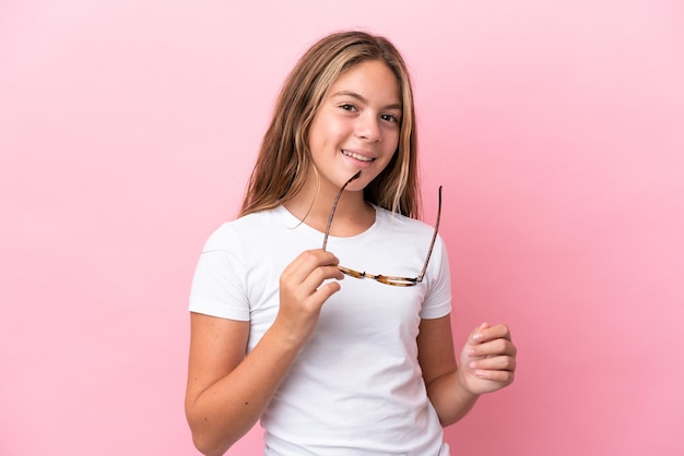 Petite fille caucasienne isolée sur fond rose avec des lunettes avec une expression heureuse