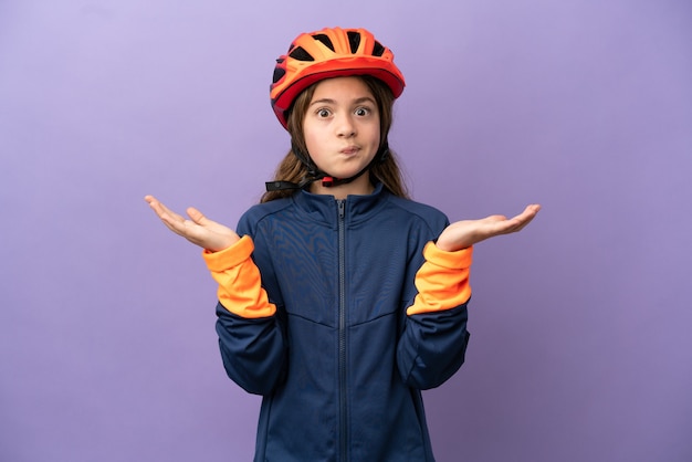 Petite fille caucasienne isolée sur fond violet ayant des doutes en levant les mains