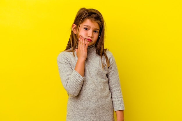 Petite fille caucasienne isolée sur jaune ayant une forte douleur aux dents, mal molaire.