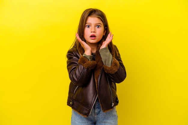 Petite fille caucasienne isolée sur jaune surpris et choqué.