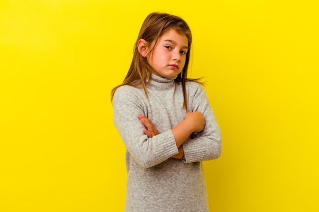 Petite fille caucasienne isolée sur jaune suspect, incertain, vous examinant.