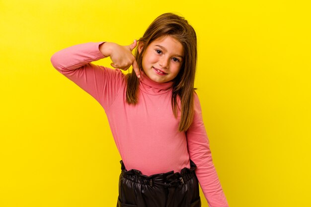 Petite fille caucasienne isolée sur personne jaune pointant à la main vers un espace de copie de chemise, fier et confiant