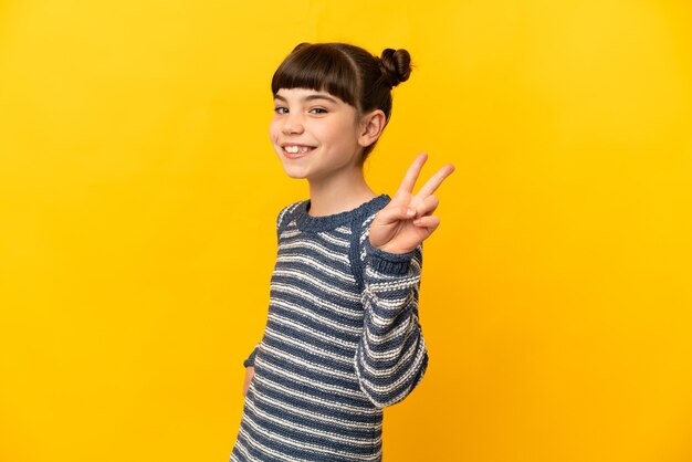 Petite fille caucasienne isolée souriant et montrant le signe de la victoire