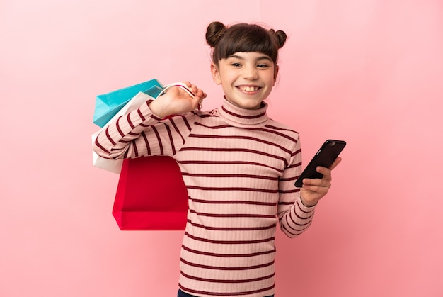 Petite fille caucasienne isolée tenant des sacs à provisions et écrire un message