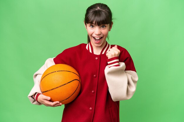 Petite fille caucasienne jouant au basket-ball sur fond isolé célébrant une victoire en position de vainqueur