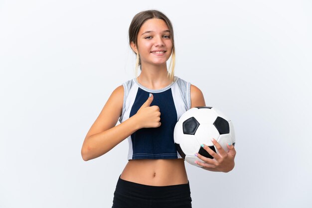 Petite fille caucasienne jouant au football isolé sur fond blanc donnant un geste du pouce vers le haut