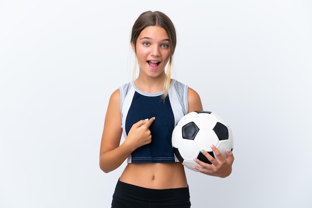 Petite fille caucasienne jouant au football isolé sur fond blanc avec une expression faciale surprise