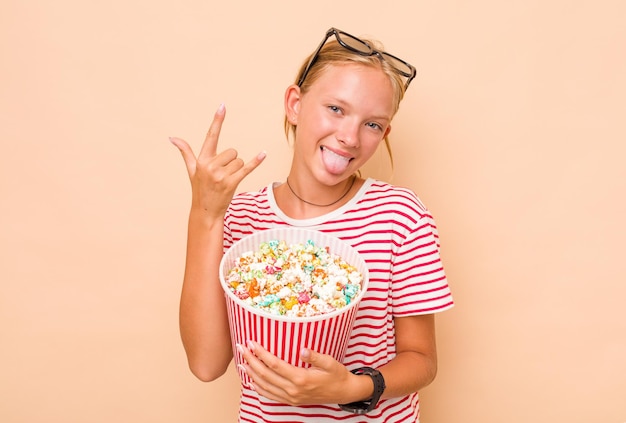 Petite fille caucasienne mangeant du pop-corn isolé sur fond beige