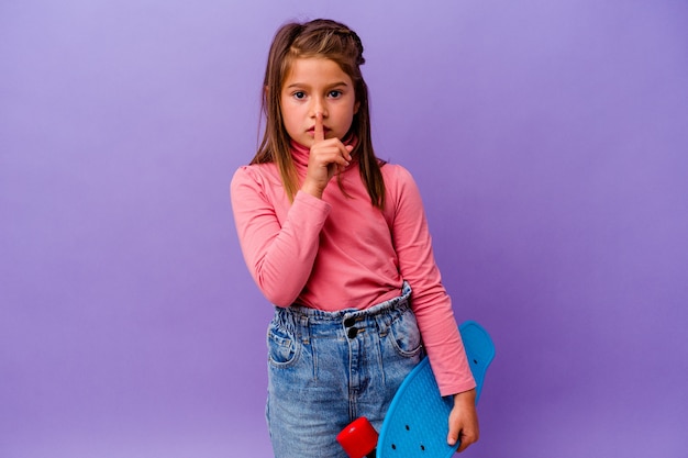 Petite fille caucasienne patineuse isolée sur fond bleu gardant un secret ou demandant le silence.