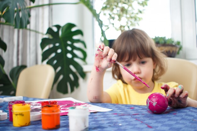 Petite fille caucasienne peint de petites figurines de jouets à l'intérieur de la maison