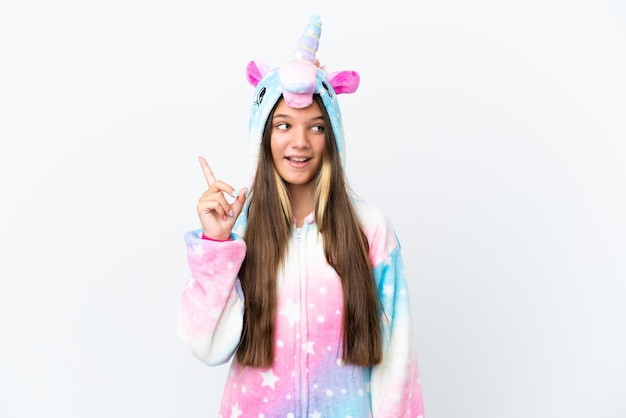 Petite fille caucasienne portant un pyjama licorne isolé sur fond blanc dans l'intention de réaliser la solution tout en levant un doigt