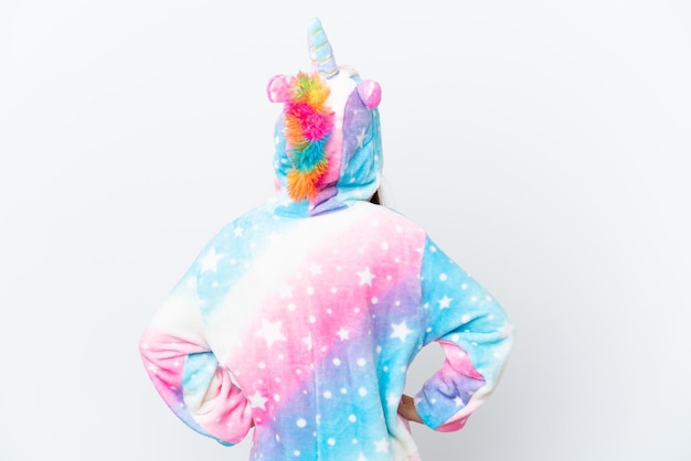 Petite fille caucasienne portant un pyjama de licorne isolé sur fond blanc en position arrière