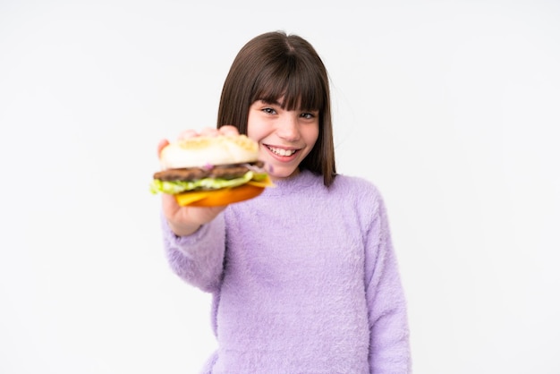 Petite fille caucasienne tenant un hamburger sur fond isolé avec une expression heureuse