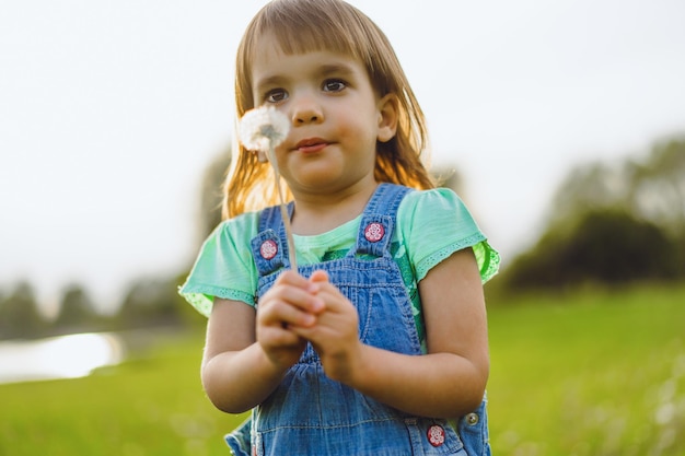 Petite fille sur un champ de pissenlit, au coucher du soleil, enfant heureux émotionnel.