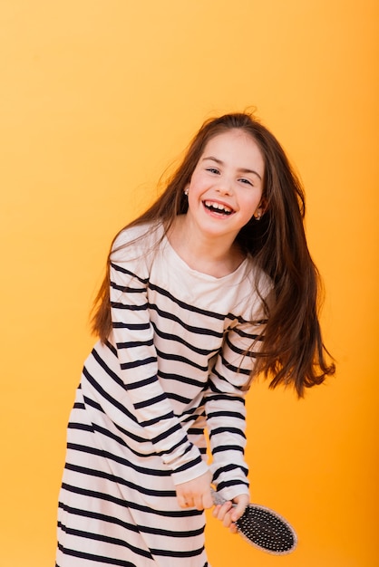 Petite fille chantant à l'aide d'une brosse à cheveux comme microphone