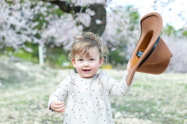 Une petite fille avec un chapeau dans un verger au printemps