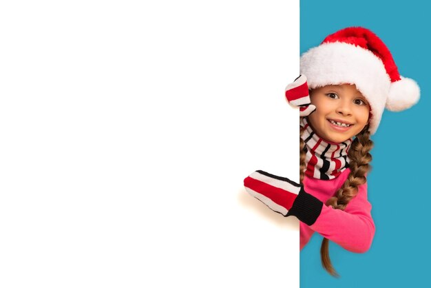 Une petite fille avec un chapeau de Noël pointe vers votre annonce