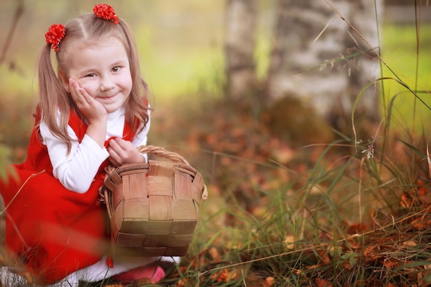 Une Petite Fille Avec Un Chapeau Rouge Et Des Robes Marche Dans Le Parc. Cosplay Pour Le Héros De Conte De Fées 
