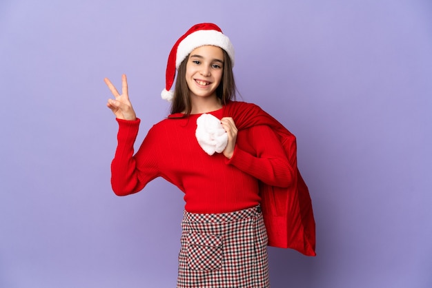 Petite fille avec chapeau et sac de Noël isolé