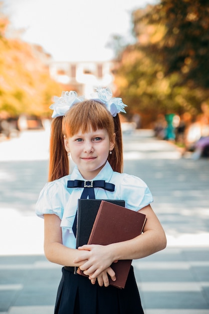 Petite fille charmante et amusante avec des livres dans les mains, le premier jour d'école ou de maternelle.