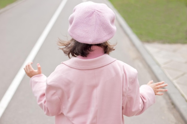 Une petite fille charmante en vêtements roses se promène le long d'une route goudronnée